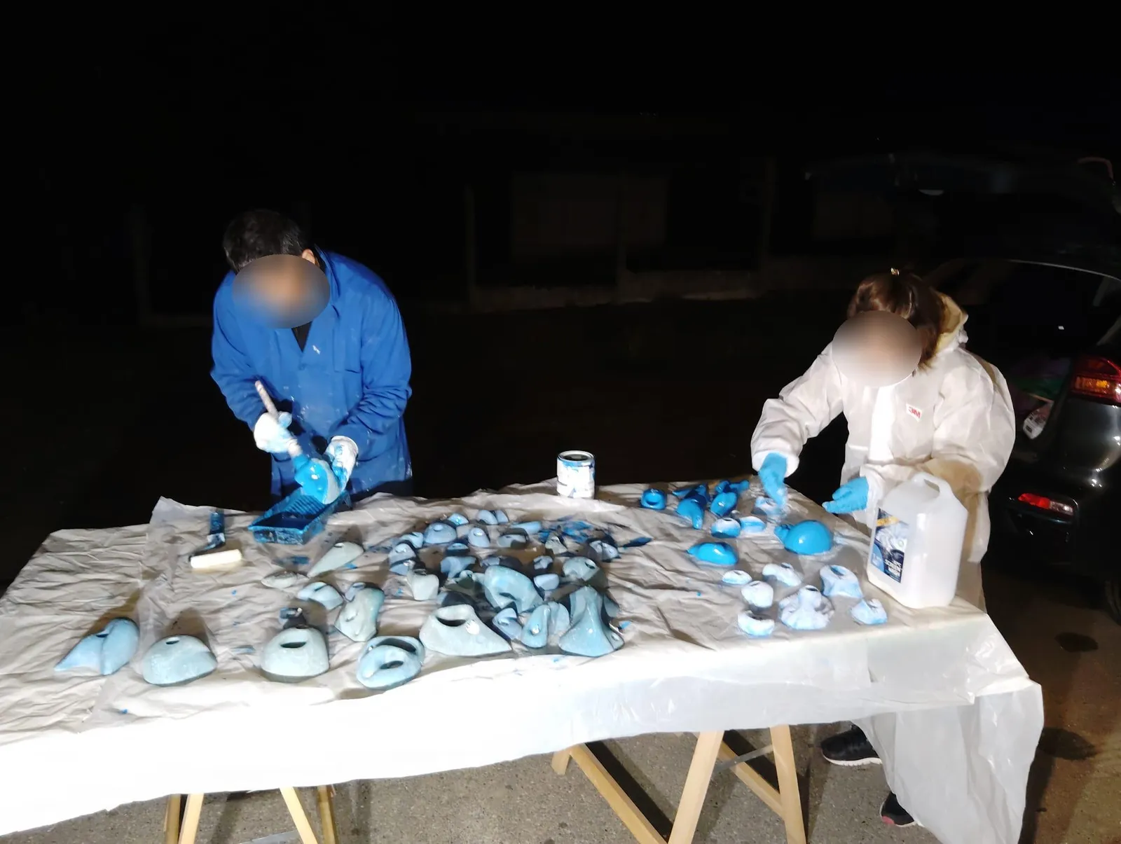 Des bénévoles rénovent des prises d’escalade bleues à l’aide de peinture.