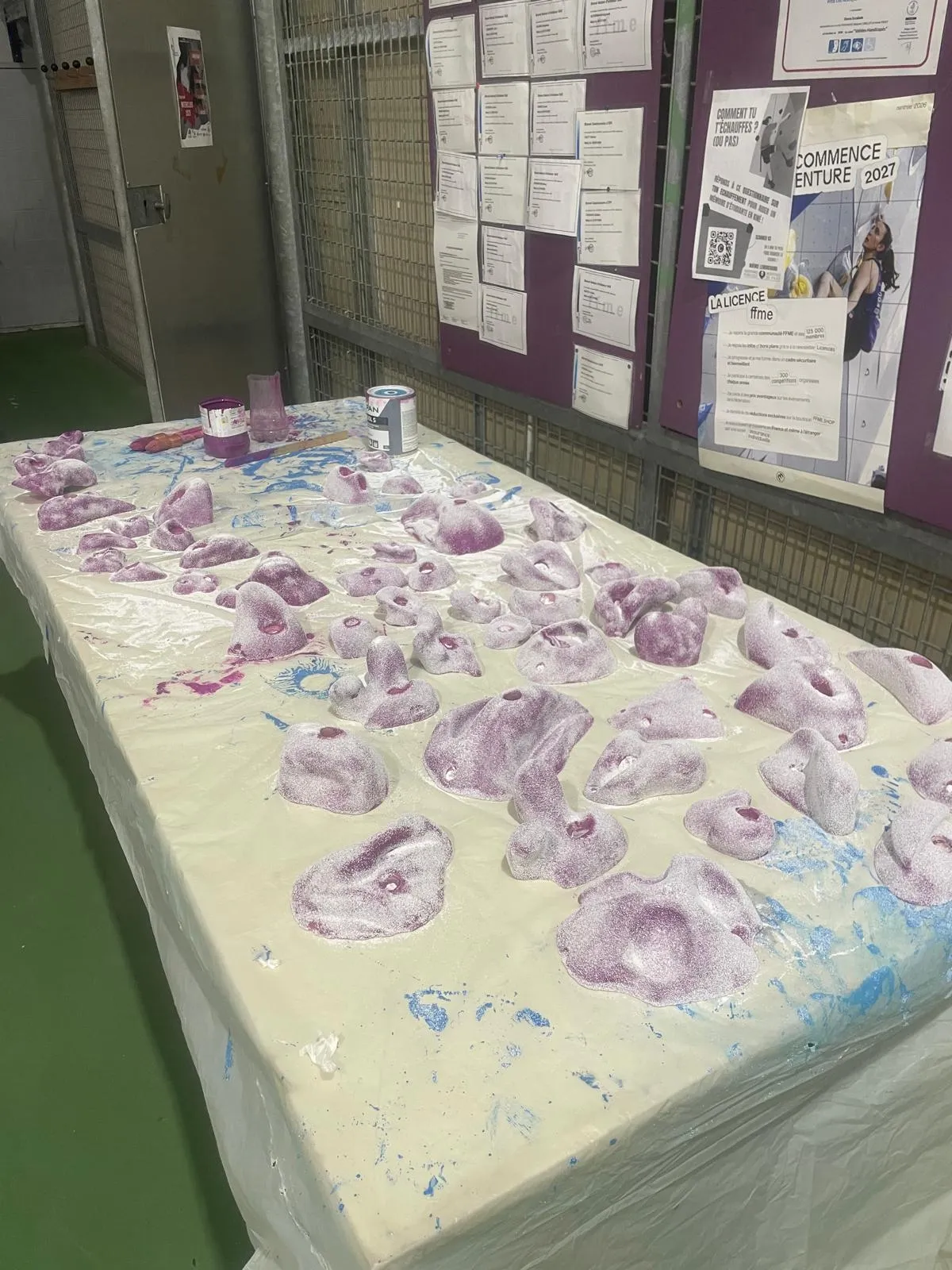 Des prises d’escalade violettes en cours de rénovation sur une table protégée.